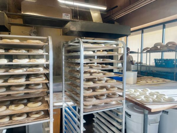 Bakery with racks of bread dough and a person working in the background Credit: Scratch Baking Co.