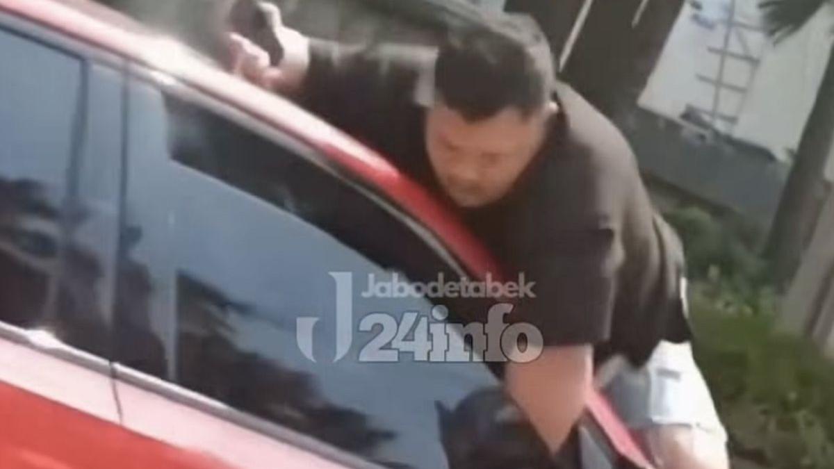 KASUS VIRAL - Seorang pria bergelantung diatas sebuah mobil berwarna merah yang melaju di kawasan Taman Anggrek Jakarta Barat viral di media sosial.