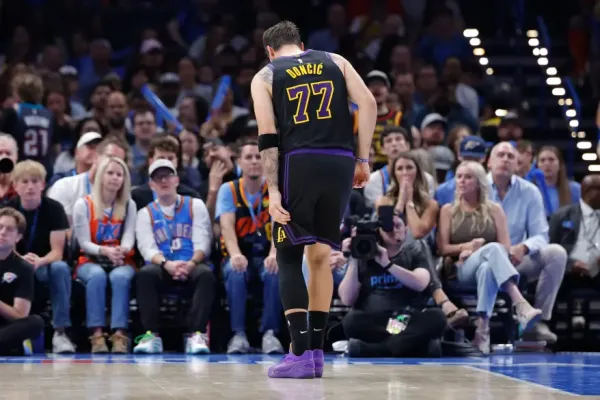 Los Angeles Lakers guard Luka Dončić wearing a black and purple jersey with the number 77, stands on the court with his back to the viewer.