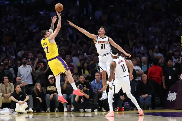 Lakers player Nikola Jokic shoots a basketball while Denver Nuggets players Aaron Gordon and Bruce Brown defend.