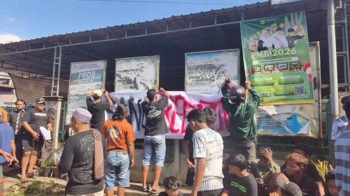 KEKERASAN SEKSUAL PONPES — Sejumlah warga membentangkan spanduk unjuk rasa di depan kediaman pengasuh Pesantren Ndolo Kusumo, Ashari, yang terjerat kasus kekerasan seksual terhadap santri di Tlogosari, Pati, Jawa Tengah, Sabtu (2/5/2026). Buntut peristiwa tersebut, Kementerian Agama berencana mencabut izin operasional pesantren dan menjamin keberlanjutan pendidikan 252 santri dengan memfasilitasi kepindahan mereka ke sejumlah sekolah rujukan.