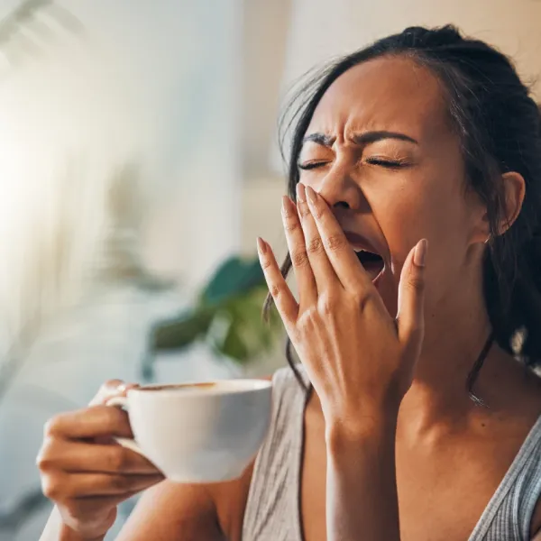 woman yawning in morning holding mug