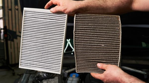 Comparing a clean cabin air filter to a dirty one during the replacement process.