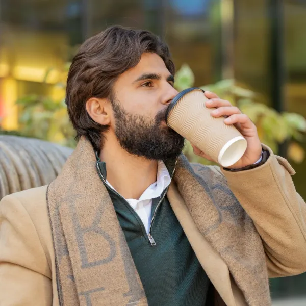 handsome man drinking out of takeout coffee cup outside
