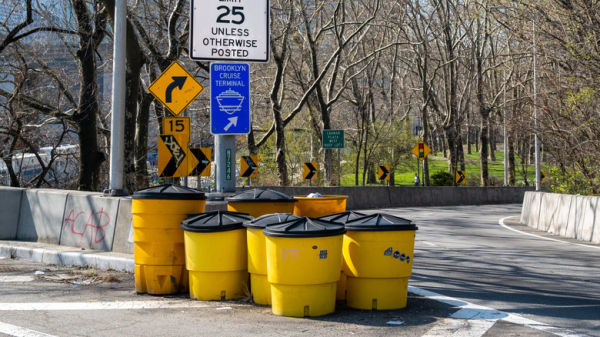 Yellow crash barrels in front of road junction in New York City.