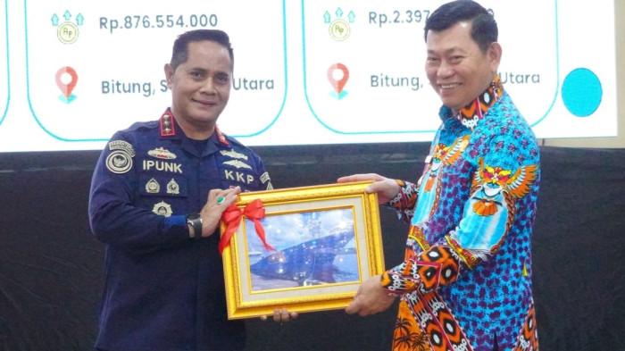 menyerahkan secara simbolis tiga kapal perikanan ke Gubernur Sulut