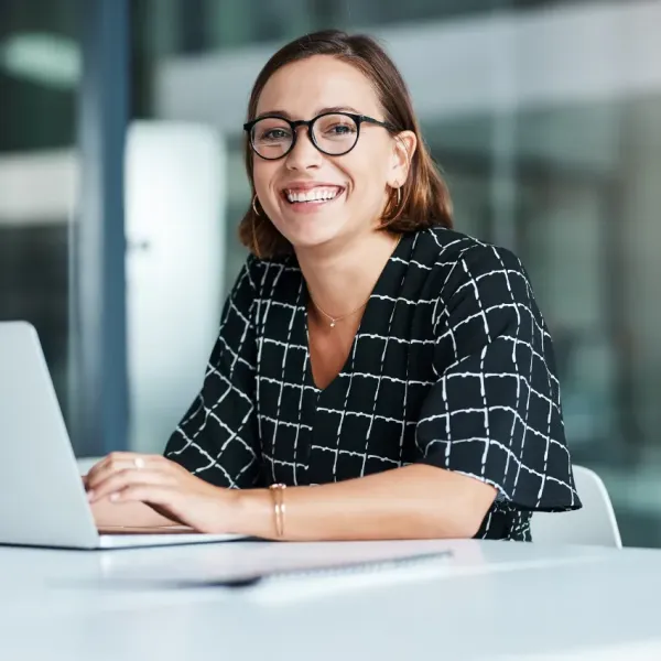 happy female employee sitting at desk in front of laptop