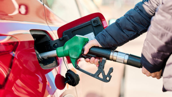 Close shot of hand squeezing fuel nozzle while filling tank with gasoline