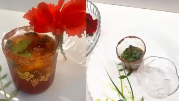 Chilled mango hibiscus mocktail served in a glass with a spiced rim, garnished with mint leaves and flower.