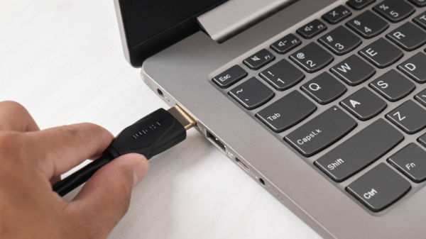 Person connecting an HDMI cable to a laptop