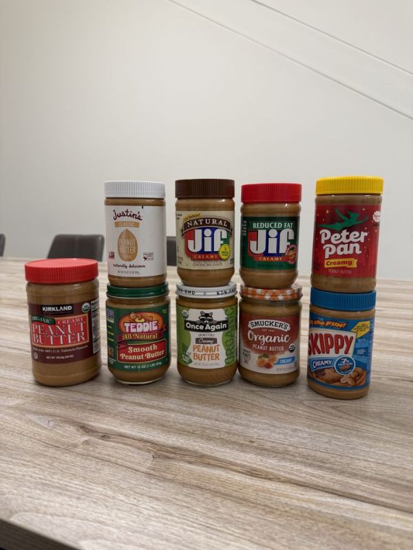 A variety of peanut butter brand jars arranged on a wooden table Credit: Jessica BallCredit: EatingWell.