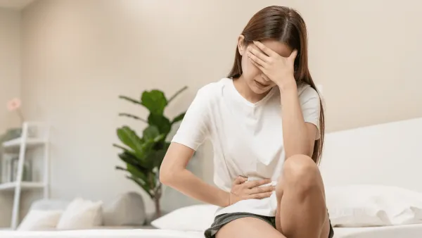 Woman whose body wants a break experiences a belly ache at home
