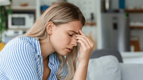 Woman who needs a break with her hand to her head with a headache