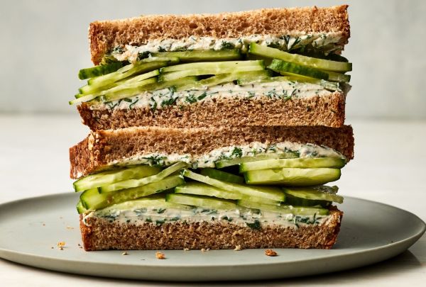 A cross section view of a sandwich on whole-wheat toast, filled with a cream cheese dill spread and sliced cucumbers Credit: Photographer: Victor Protasio, Food Stylist: Margaret Dickey, Prop Stylist: Lydia Pursell