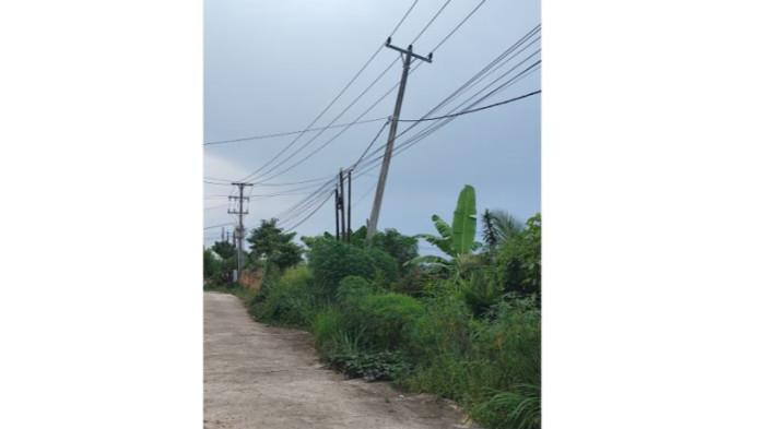MIRING - Tiang listrik di  Perumahan Griya Assalam di Kelurahan Mayang Mangurai, Kecamatan Alam Barajo, Kota Jambi miring. Setahun dilaporkan ke PLN tak juga ada tindaklanjutnya.