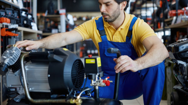 A man worker is diligently working on an air compressor in a store setting