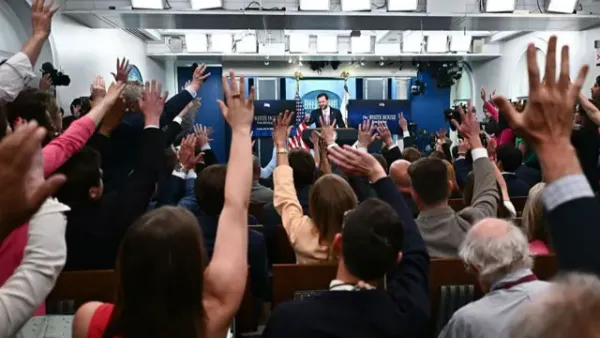 Hands raised by journalists as Vance fields questions from the podium