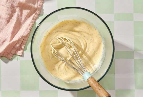 A bowl of slaw dressing with a whisk on a checkered surface Credit: Diana Christruga