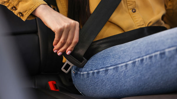 Woman fastening safety seat belt inside modern car, closeup