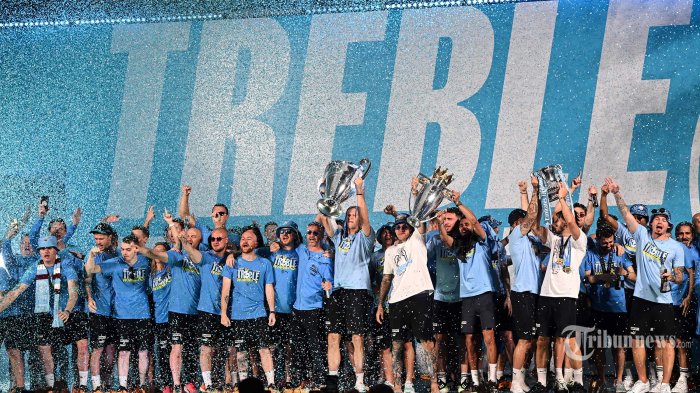 Para pemain Manchester City merayakan di atas panggung dengan trofi mereka setelah parade kemenangan bus atap terbuka untuk kemenangan Piala Eropa, Piala FA, dan Liga Premier mereka, di Manchester, Inggris utara pada 12 Juni 2023. Manchester City akhirnya mencicipi kejayaan Liga Champions pada hari Sabtu sebagai gol babak kedua Rodri memberi favorit kemenangan 1-0 atas Inter Milan di final yang menegangkan, memungkinkan tim Pep Guardiola menyelesaikan treble yang luar biasa. Setelah mengklaim gelar Liga Premier kelima dalam enam musim, dan menambahkan Piala FA, City adalah klub Inggris pertama yang memenangkan treble sejak Manchester United pada 1999. (Photo by Oli SCARFF / AFP)