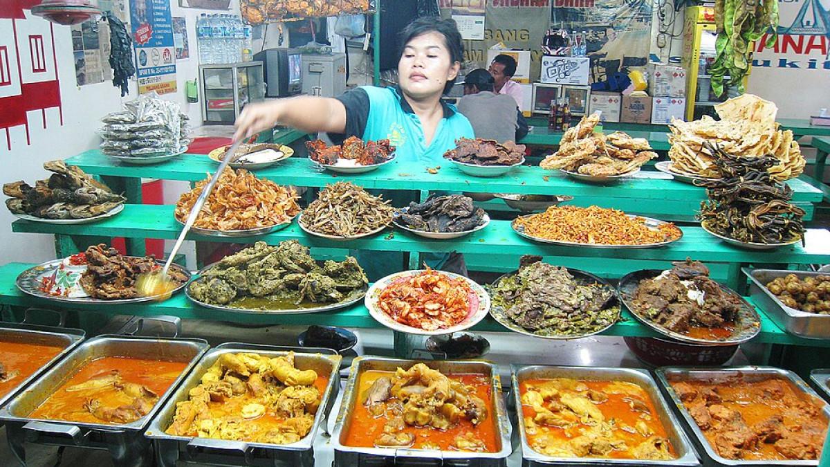 NASI KAPAU - Ilustrasi sajian Nasi Kapau Sabana Bana Bukittinggi yang cocok untuk makan siang enak dekat Stasiun Pasar Senen. Warung makan ini populer karena menyediakan berbagai lauk khas Sumatera Barat seperti gulai tunjang, ayam pop, dan gulai nangka dengan rasa otentik.