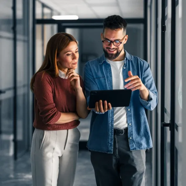 co-workers looking at tablet in office after company implements cost-cutting measures
