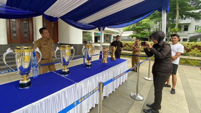 PIALA PERSIB - Sejumlah pekerja saat berfoto dengan Piala Persib Bandung yang dipajang di Balai Kota Bandung, Senin (26/5/2026).
