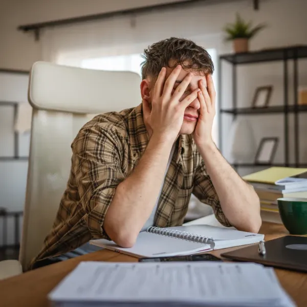 stressed male college student with head in hands
