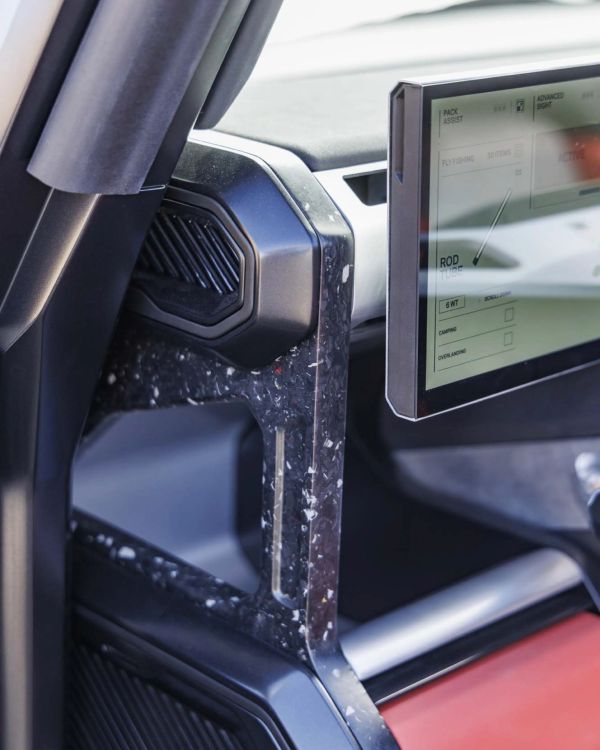 Close-up of a car interior showing a black speckled pillar, air vent, and a touchscreen display with fishing-related options.