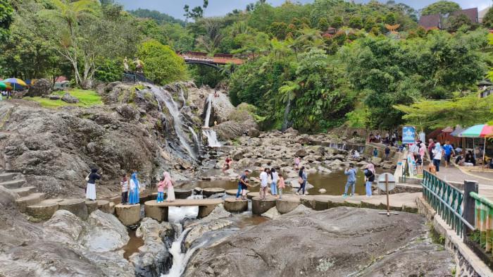 WISATA BANYUMAS - Sejumlah wisatawan saat sedang menikmati pemandangan alam di kawasan Lokawisata Baturraden, Kabupaten Banyumas, Kamis (1/1/2026). Sejumlah keluarga tampak menggelar tikar di bawah rindangnya pepohonan dan membuka bekal nasi dan lauk pauk, lalu menyantapnya bersama sanak saudara.