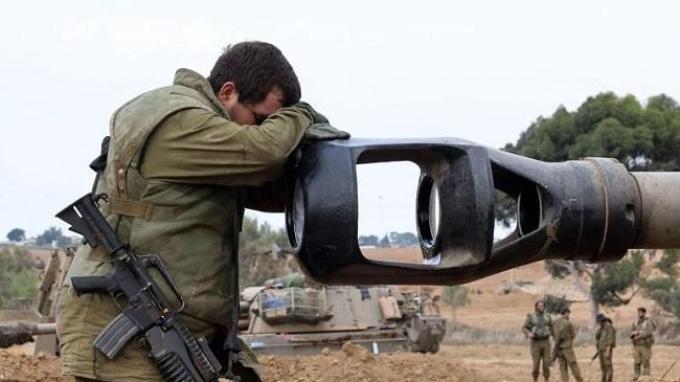 Seorang tentara Israel di dekat perbatasan Jalur Gaza tampak menyandarkan kepalanya ke uung turret, laras meriam tank.