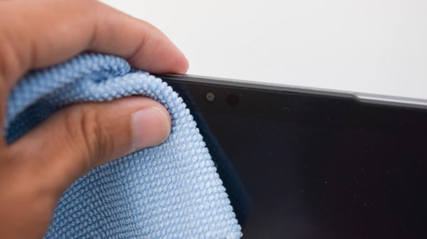 Person using a microfiber cloth to clean a laptop screen and webcam.