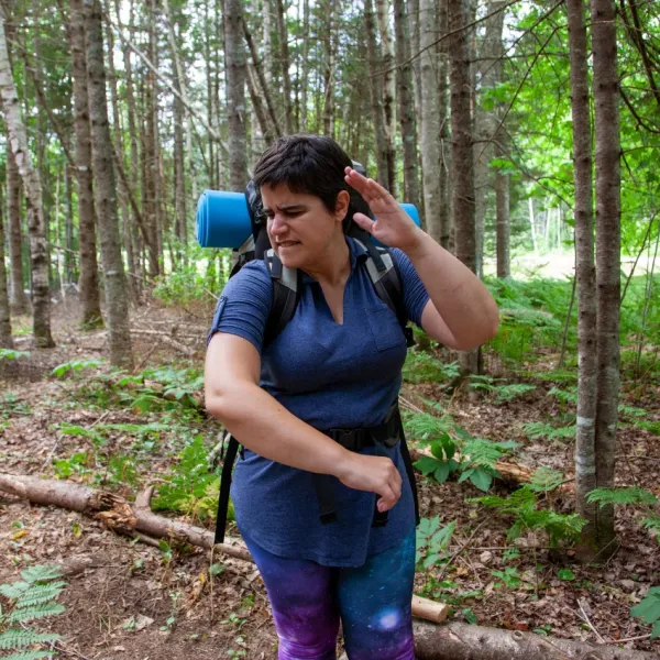 woman swatting at a mosquito on a hike