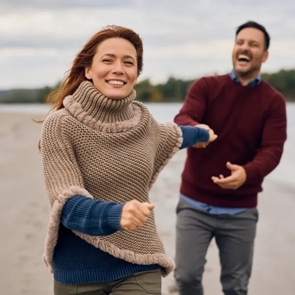 couple laughing while walking on beach