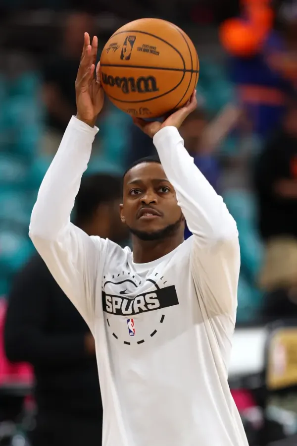 De'Aaron Fox of the San Antonio Spurs warms up, holding a basketball above his head.