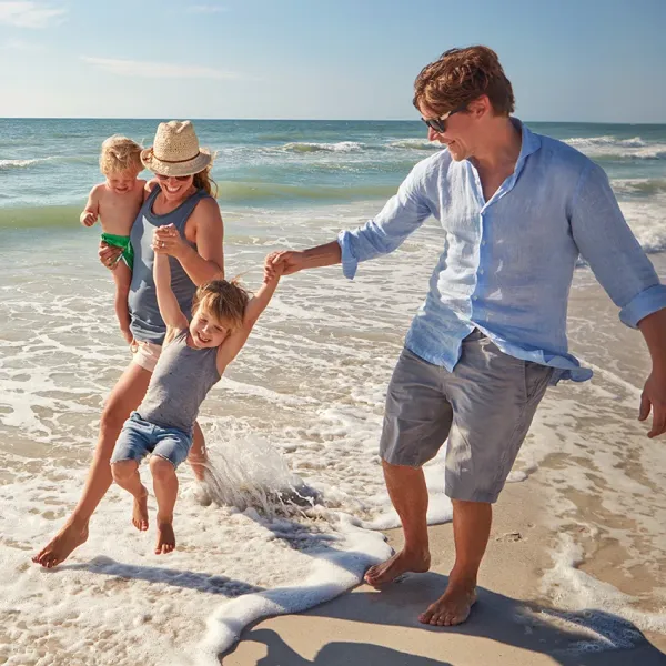 gen x couple playing with their children on beach