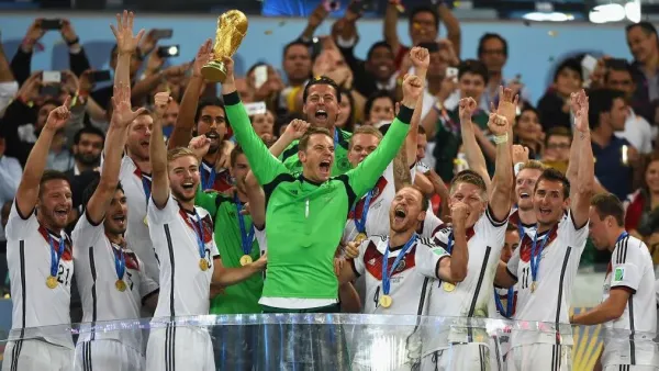 Dipimpin oleh kapten sekaligus penjaga gawang Manuel Neuer yang memegang trofi Piala Dunia dan mengenakan kaus hijau, para pemain tim Jerman merayakan kemenangan mereka atas Argentina pada turnamen 2014. Para pemain mengenakan medali di leher mereka.