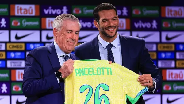Carlo Ancelotti menerima kaus tim nasional Brasil berwarna kuning-hijau dari presiden Konfederasi Sepak Bola Brasil (CBF), Samir Xaud, pada 26 Mei 2025 di Rio de Janeiro, Brasil. Keduanya mengenakan jas dan dasi serta tersenyum.