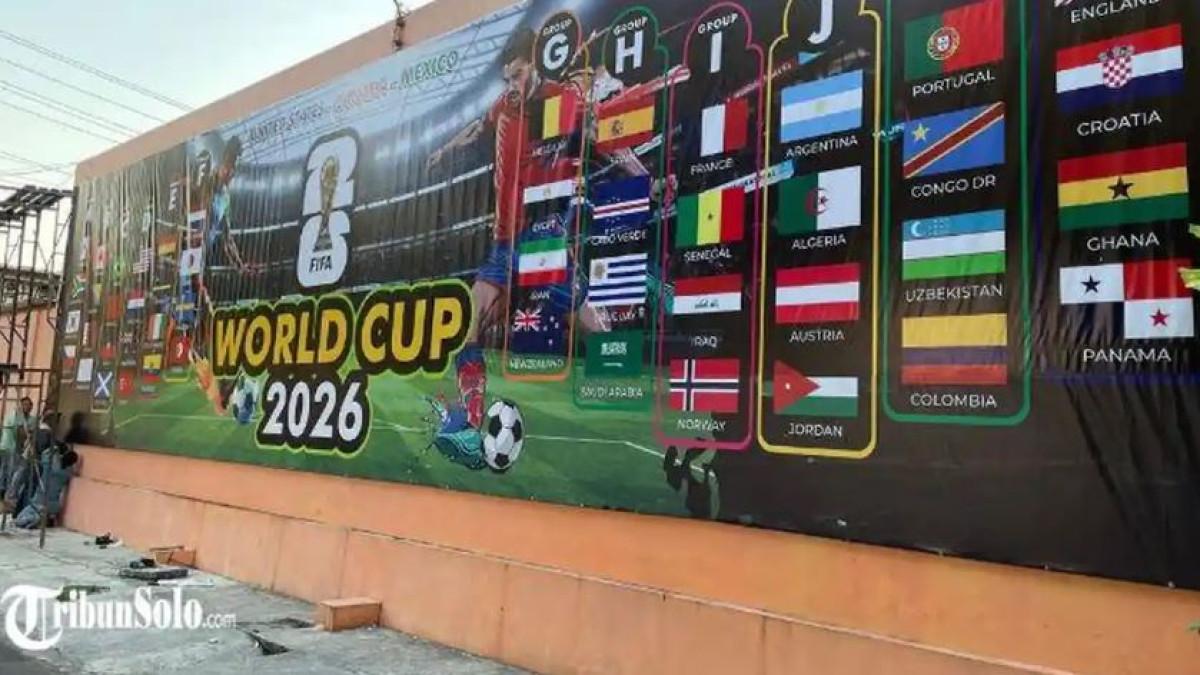 SAMBUT PIALA DUNIA - Meriahkan dan beri kejutan tetangga, warga Karangasem Kota Solo pasang baliho besar berisi gambar peserta Piala Dunia 2026, Kamis (11/6/2026). Baliho berukuran 10 x 3 meter itu terpasang di tembok rumah yang menghadap langsung ke Lapangan Karangasem.