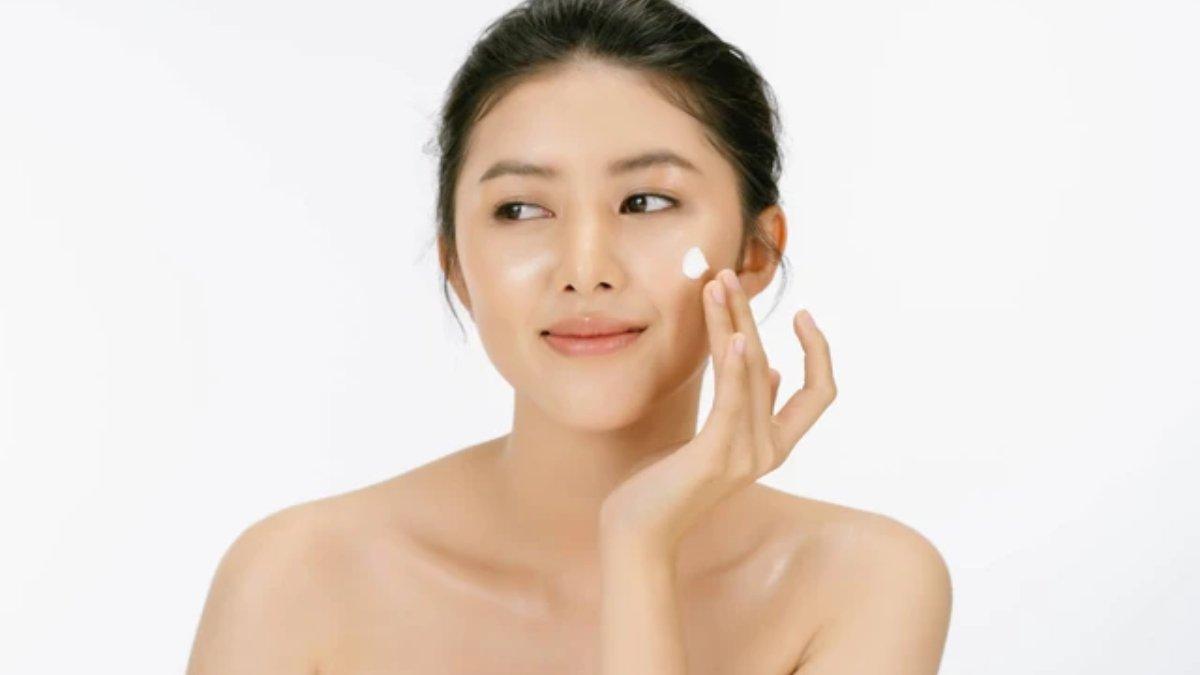 Ilustrasi wanita menggunakan moisturizer untuk mendapatkan kulit wajah glowing.