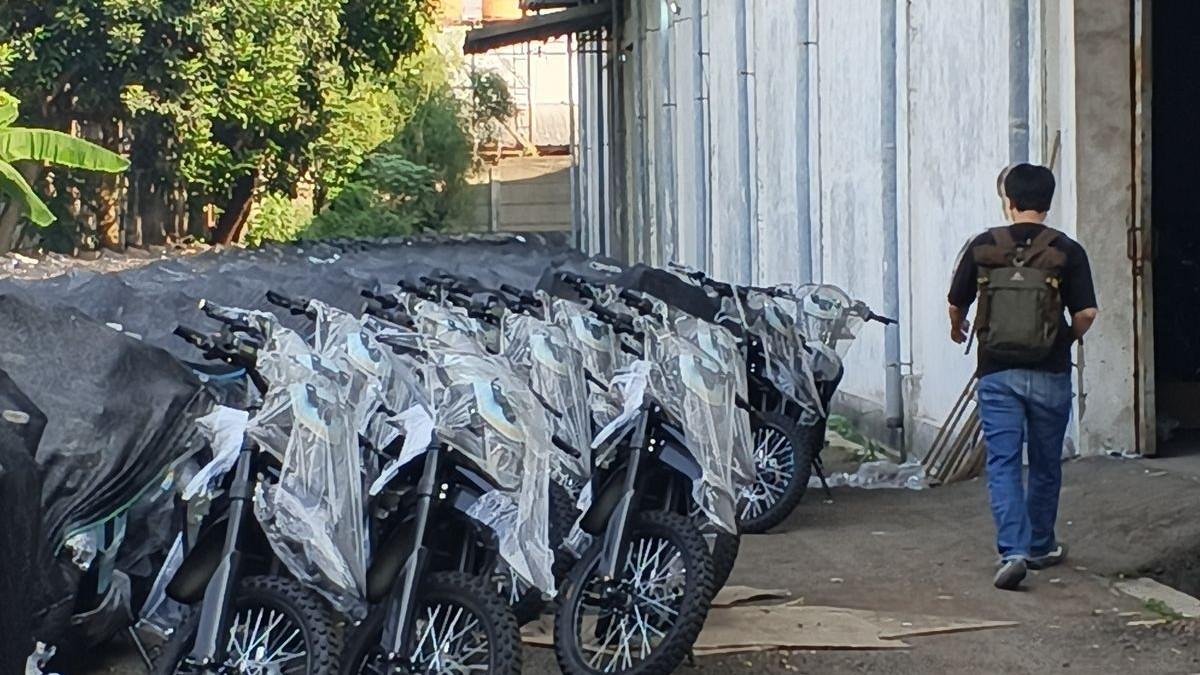 KORUPSI MBG - Kondisi lokasi penyimpanan motor listrik MBG di Kawasan Industri Sentul, Jalan Olympic Raya Kavling B6, Desa Sentul, Kecamatan Babakan Madang, Kabupaten Bogor, Jawa Barat, Kamis (11/6/2026). Di area terbuka seluas lebih dari satu hektare itu, tampak tiga deretan panjang motor listrik Emmo JVX GT berwarna biru-hitam tersusun rapi. Sebagian besar kendaraan jenis trail dan matik itu masih terlihat baru karena terbungkus plastik.