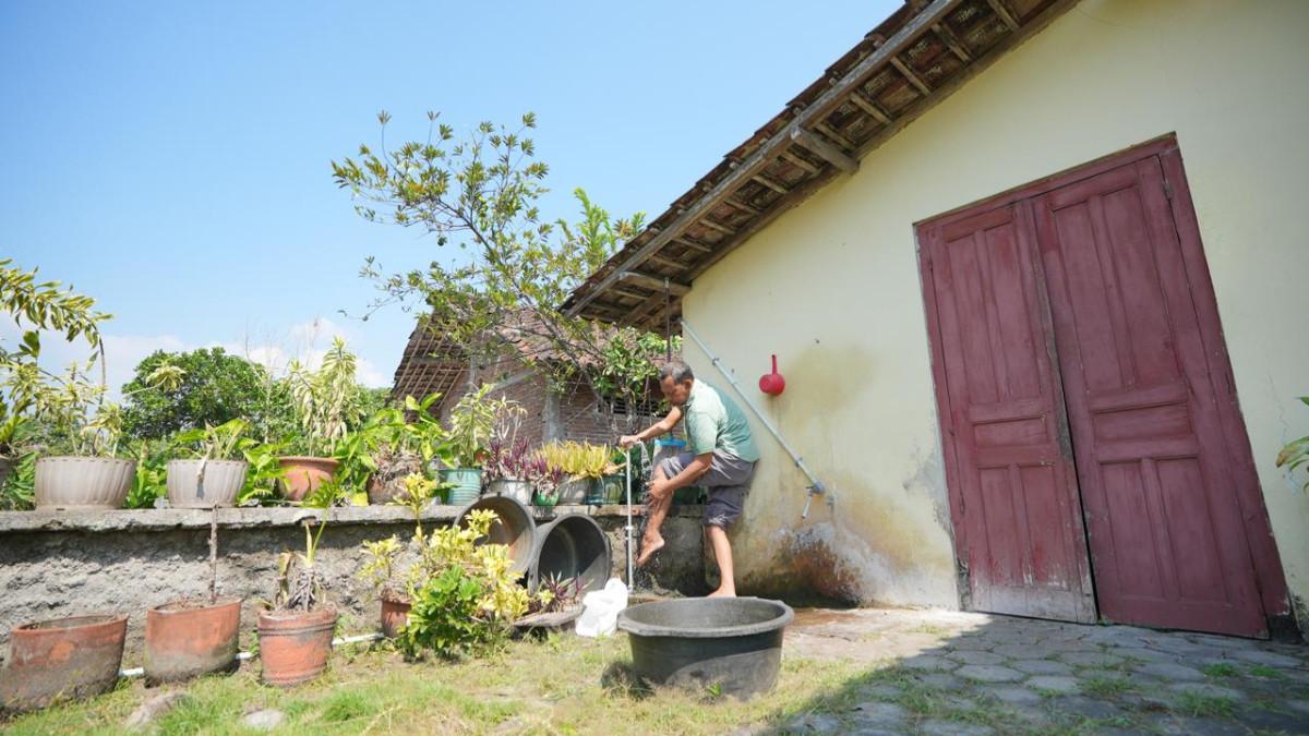 KABAR KLATEN - Sukrisnanto saat menggunakan air PDAM Klaten yang baru dipasang di rumahnya.