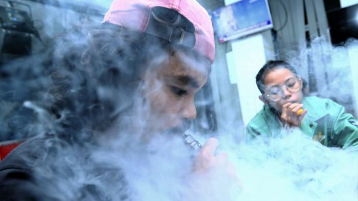 PENGGUNA VAPE - Pengguna vape menggunakan rokok elektronik di sebuah aktivitas. Anggapan, bahwa asap vape adalah “versi bersih” dari rokok tembakau, vape lebih aman dari rokok tembakau, atau vape merupakan solusi untuk berhenti merokok merupakan anggapan yang salah. Spesialis paru RS Persahabatan Jakarta, Prof. Dr. dr. Agus Dwi Susanto, Sp.P(K) menyebut, di balik uap vape beraroma manis tersebut, para dokter spesialis paru melihat sebuah fakta tersembunyi berupa ancaman kesehatan ancaman kesehatan 