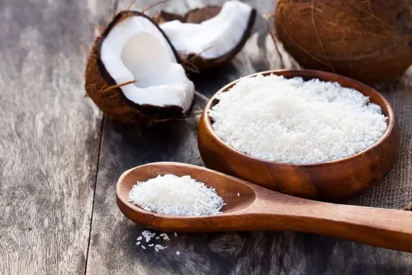Cracked coconut and flakes on rustic wooden table background