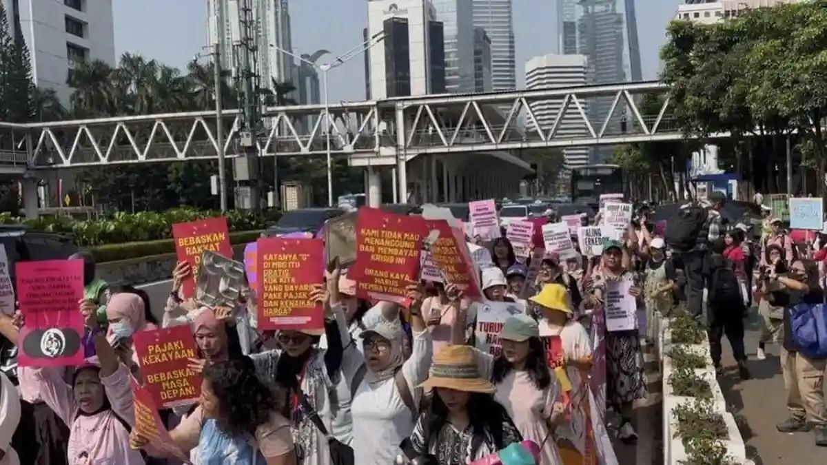 DEMO DI JAKARTA - Sejumlah perempuan yang tergabung dalam Aliansi Perempuan Indonesia membawa berbagai poster tuntutan saat menggelar aksi long march di kawasan Jalan Jenderal Sudirman, Jakarta, Kamis (18/6/2026). Dalam aksinya, puluhan massa yang mengenakan pakaian serba pink dan daster tersebut mendesak pemerintah untuk menurunkan harga kebutuhan pokok, menciptakan lapangan kerja, serta menuntut penghentian program Makan Bergizi Gratis (MBG) karena dianggap tidak menjawab persoalan ekonomi
