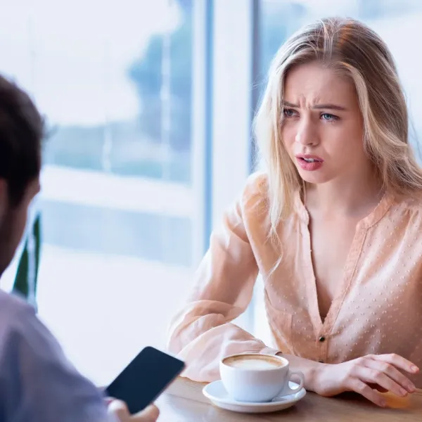 man distracted by his phone while girlfriend gets annoyed