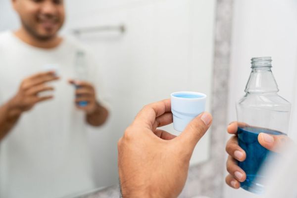 Young man is gargling with a blue mouthwash. For good dental health and fresh bad breath. Take care and good dental health fresh breath with mouthwash Young man is gargling with a blue mouthwash. For good dental health and fresh bad breath. Take care and good dental health fresh breath with mouthwash