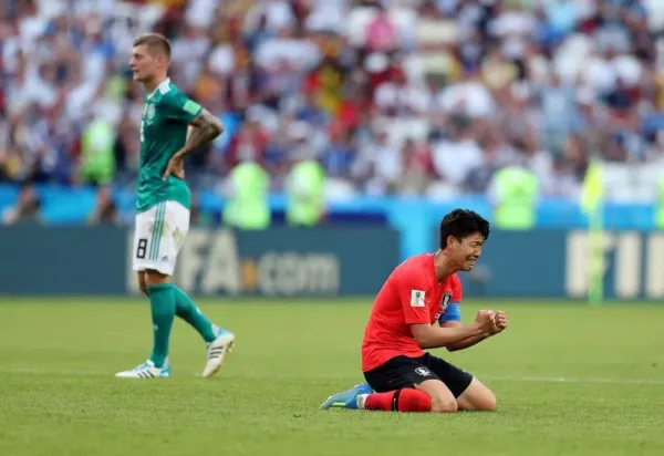 KAZAN, RUSSIA - JUNE 27: Son Heung-Min of Korea Republic sinks to his knees as he celebrates following his sides victory, as a dejected Toni Kroos of Germany can be seen walking off after the 2018 FIFA World Cup Russia group F match between Korea Republic and Germany at Kazan Arena on June 27, 2018 in Kazan, Russia. (Photo by Catherine Ivill/Getty Images)
