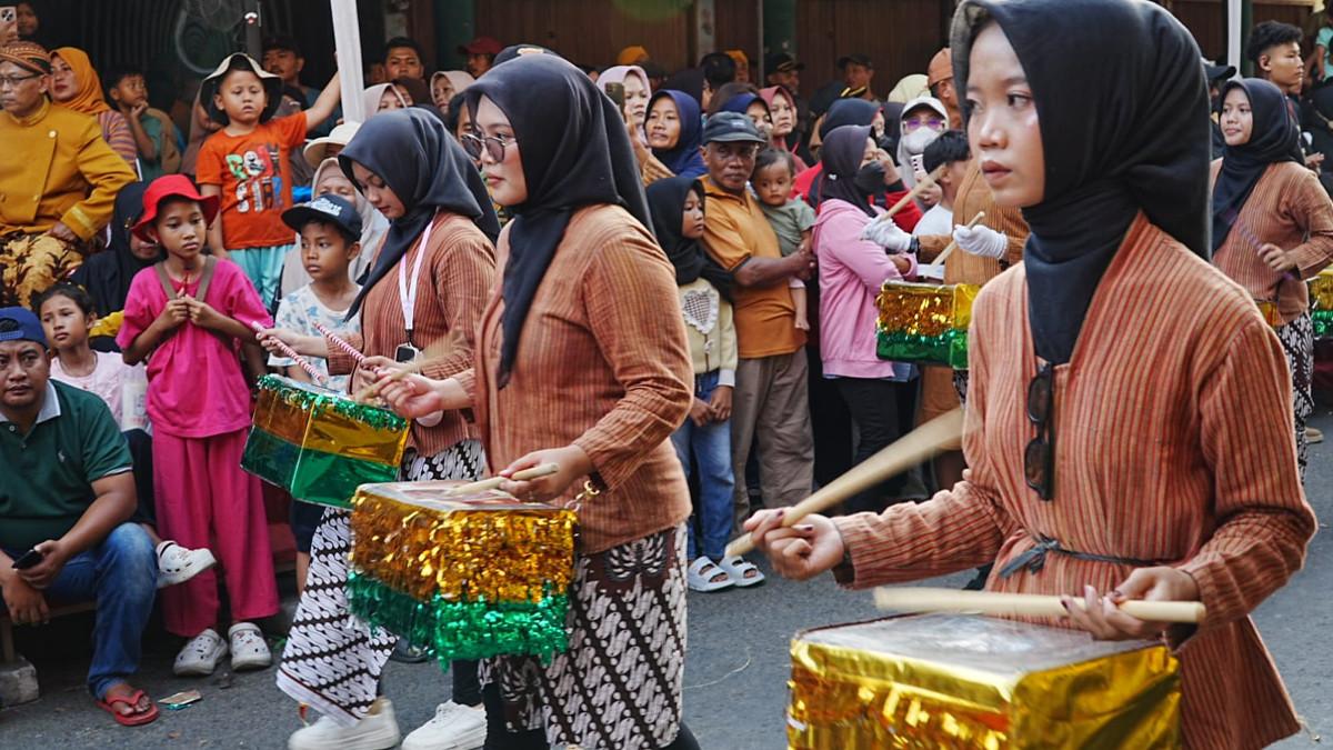GREBEG PASAR MASARAN - Kontingen drumblek yang memanfaatkan peralatan berbahan aluminium dan wadah bekas makanan sebagai alat musik saat Kirab Grebeg Pasar Masaran Cawas XI di Kecamatan Cawas, Klaten, Sabtu (20/6/2026).