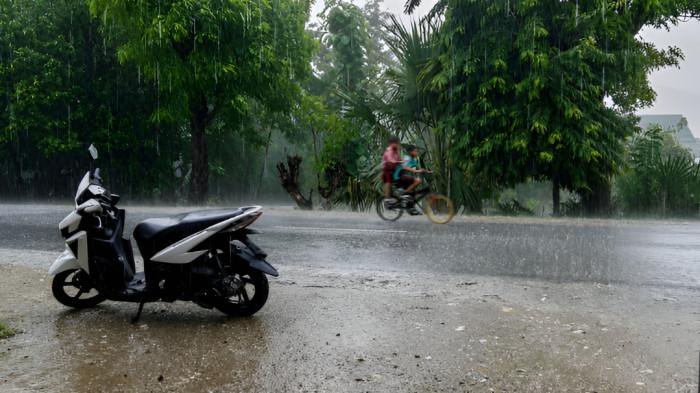 MANDI HUJAN- Dua orang bocah berboncengan naik sepeda sedang mandi hujan di sore hari. Tampak keduanya basah kuyup.